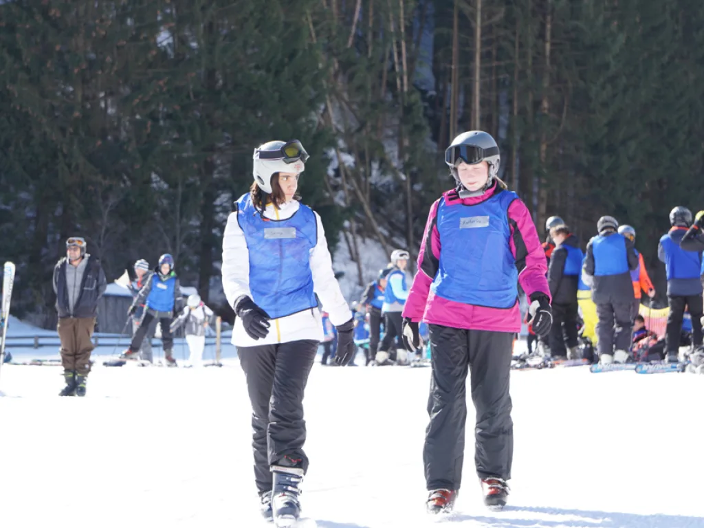 Zwei Jugendliche gehen über die Piste zum Lift.